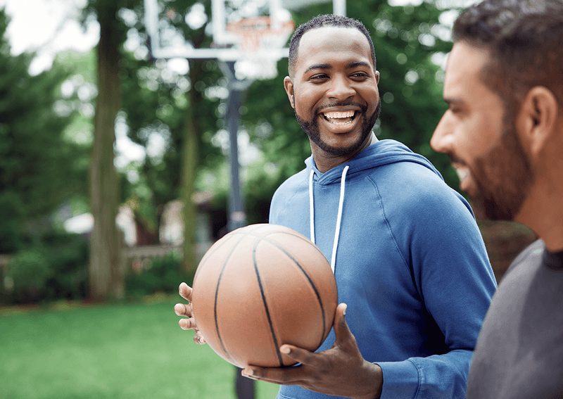 Man holding a basketball laughing with a friend